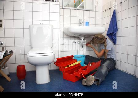Junge Frau bei der Reparatur eines defekten Wasserhahn im Badezimmer Stockfoto