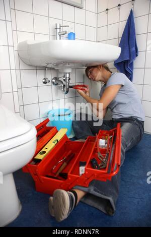 Junge Frau bei der Reparatur eines defekten Wasserhahn im Badezimmer Stockfoto