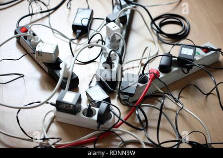 Mehrere Steckerleisten sind für den Anschluss von mehreren elektrischen Geräten, Gewirr von Kabeln, Steckern und Netzteile Stockfoto