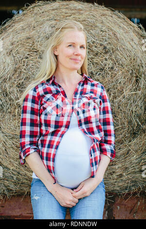 Schwangere Frau lehnte sich auf haybale Stockfoto