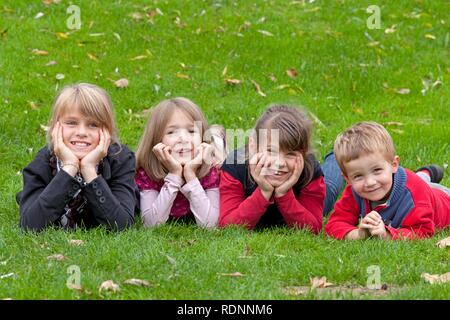 Vier Kinder liegen auf einer Wiese Stockfoto