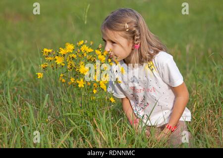 Kleines Mädchen Blumen riechen Stockfoto