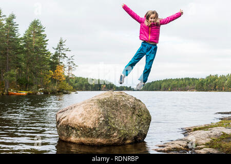 Mädchen Sprung vom Felsen in See Stockfoto