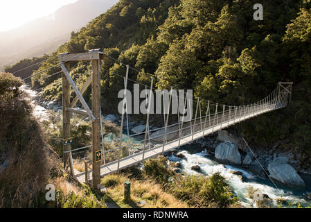 Beginn der Rob Roy Gletscher führt Wanderer über den Matukituki River über eine Hängebrücke in einen Buchenwald im Matukituki Valley in der Nähe von Stockfoto