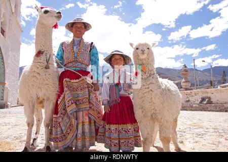 Frau und Mädchen mit Lama und Alpaka in Maca in der Nähe von Colca Canyon, Peru, Südamerika Stockfoto