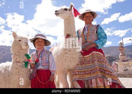 Frau und Mädchen mit Lama und Alpaka in Maca in der Nähe von Colca Canyon, Peru, Südamerika Stockfoto
