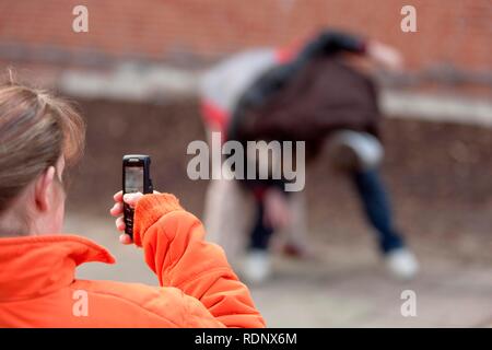 Zwei Jungen kämpfen und von einem Mädchen mit dem Handy gefilmt wird, Reenactment Stockfoto