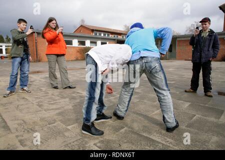 Zwei kämpfenden Jungen werden von drei anderen Jugendlichen mit Ihrem Mobiltelefon gefilmt, Reenactment Stockfoto