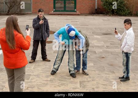 Zwei kämpfenden Jungen werden von drei anderen Jugendlichen mit Ihrem Mobiltelefon gefilmt, Reenactment Stockfoto