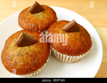 Eine Platte der Banana Muffins mit Milch Schokolade Klumpen serviert auf hölzernen Tisch Stockfoto