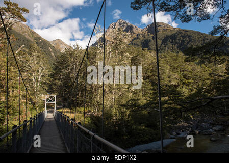 Eine Hängebrücke in einen Buchenwald führender markiert den Beginn des Routeburn Track in der Nähe von Burnie in Neuseeland. Stockfoto