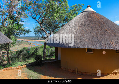 Traditionelle Gasthäuser & Pensionen in strohgedeckte rondovals mit Blick auf den Olifants Fluss in Olifants Restcamp, Krüger Nationalpark, Südafrika Stockfoto