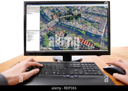 Person sitzen an einem Computer arbeiten mit Google Street View, Anzeige, auf der ein Bild von einem Teil der Innenstadt von Amsterdam. Stockfoto