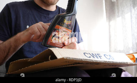 Straßburg, Frankreich - Apr 15, 2018: der Mensch un-Verpackung unboxing Amazon Prime Karton zu Hause Austragsöffnung Karton und Amazon Paket Meguiars car Kosmetik Leder Conditioner Stockfoto