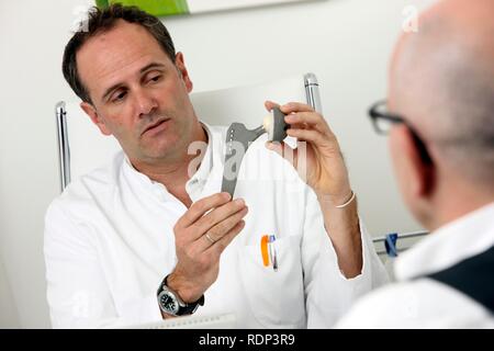 Arztpraxis, Arzt im Gespräch mit dem Patienten, Arzt erklärt, wie ein künstliches Hüftgelenk funktioniert Stockfoto
