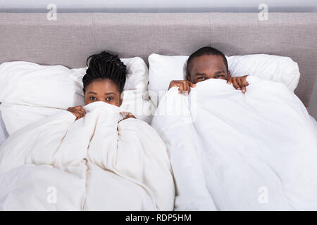 Hohe Betrachtungswinkel und einer afrikanischen Paar versuchen, zu verstecken in der Decke Stockfoto