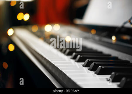 Piano keys mit schönen gelben Lichter Bokeh im Hintergrund, Piano keys mit der Weihnachtsbeleuchtung Stockfoto