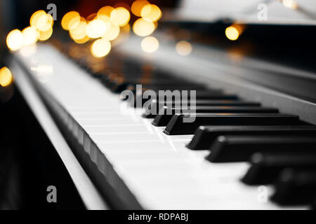 Piano keys mit schönen gelben Lichter Bokeh im Hintergrund, Piano keys mit der Weihnachtsbeleuchtung Stockfoto