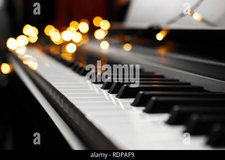 Piano keys mit schönen gelben Lichter Bokeh im Hintergrund, Piano keys mit der Weihnachtsbeleuchtung Stockfoto