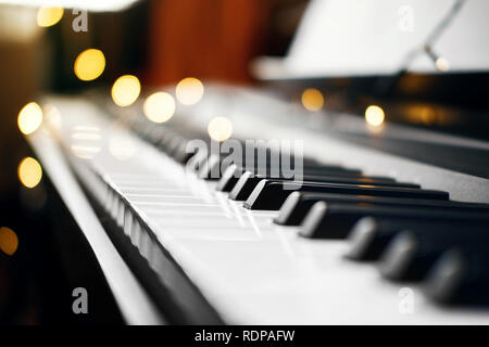 Piano keys mit schönen gelben Lichter Bokeh im Hintergrund, Piano keys mit der Weihnachtsbeleuchtung Stockfoto