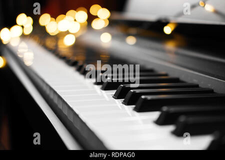 Piano keys mit schönen gelben Lichter Bokeh im Hintergrund, Piano keys mit der Weihnachtsbeleuchtung Stockfoto