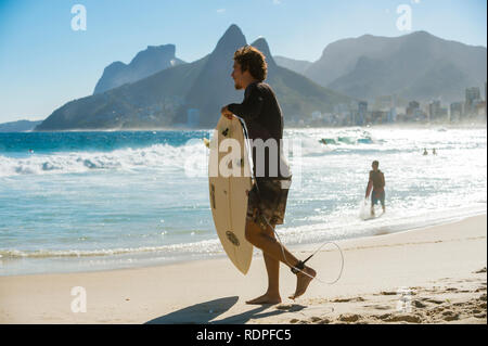 RIO DE JANEIRO - 20. MÄRZ 2017: jungen brasilianischen Surfer tragen ihre Surfbretter in der Brandung zerschlagen von Arpoador am Strand von Ipanema Stockfoto