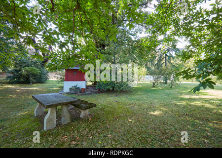 Alten steinernen Tisch und Bank mit Garten- und Kastanienbäumen in einem sonnigen Tag, Italien Stockfoto