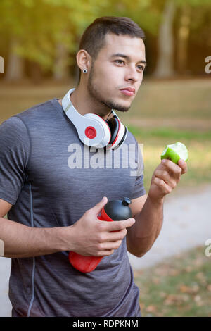 Runner latin Mann essen apple Hochformat joggen laufen sport training Fitness im Freien Stockfoto