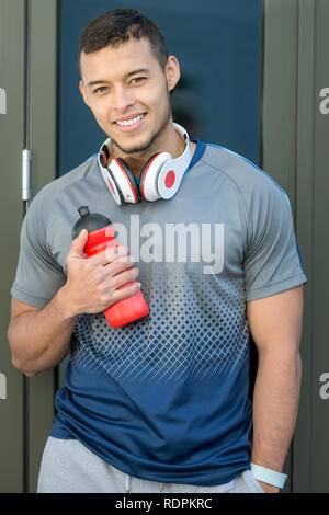 Lächelnden jungen latin Mann Wasser Flasche runner Hochformat laufen sport training Fitness im Freien Stockfoto
