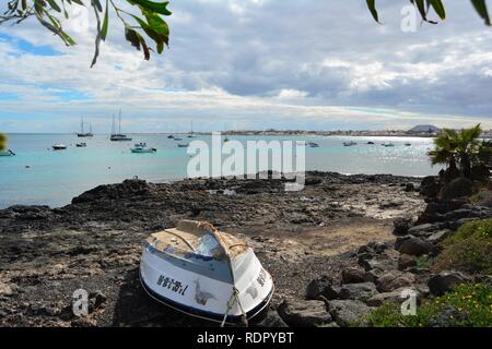 Alten, verlassenen Boot an der felsigen Küste von Corralejo. Türkisfarbene Meer und herrlichen Himmel im Hintergrund. Fuerteventura, Spanien. Stockfoto