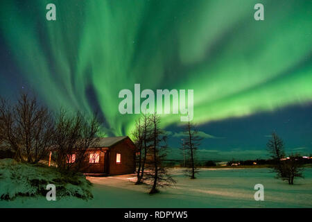 Awesome Nordlichter über ein wunderschönes Haus mit Schnee bedeckt. Bild wurde in Island im November 2017. Stockfoto