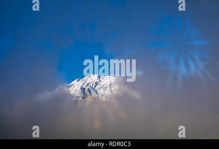 Blick durch ein milchglas mit einem klaren Sterne auf die schneebedeckten Alpen. Stockfoto