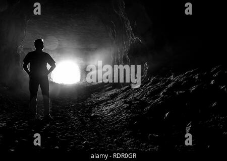 Die Silhouette eines Mannes, der in den Gängen eine gruselige dunkle Höhle. Stockfoto