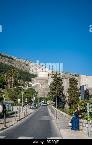 Dubrovnik, Kroatien - April 2018: Weibliche touristische ruht neben ihr Trolley Reisetasche vor den historischen Mauern der Altstadt Stockfoto