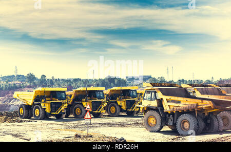 Gelbe Muldenkipper in der Mine von Riotinto in der Zeile setzen, mit traffic signal der Ausfahrt der Lkw im Vordergrund und blauer Himmel und Wolken Stockfoto