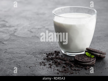 Glas Milch und Schwarz sandwich Cookies auf schwarzen Stein Küchentisch Hintergrund. Stockfoto