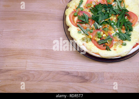 Fragment der gekochten appetitliche Pizza mit Tomaten, mais und Erbsen auf runden Platte auf Holz- Hintergrund der Ansicht von oben Stockfoto