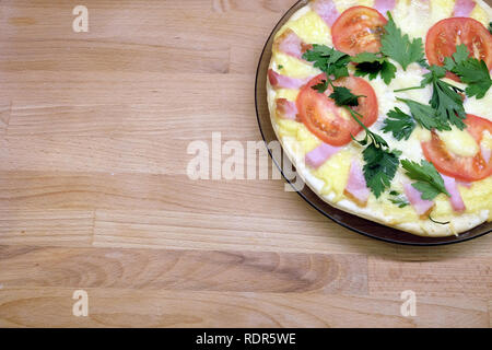 Fragment der Platte mit vorbereiteten appetitliche Pizza mit Tomaten, Schinken und Käse auf Holz- Hintergrund der Ansicht von oben Stockfoto