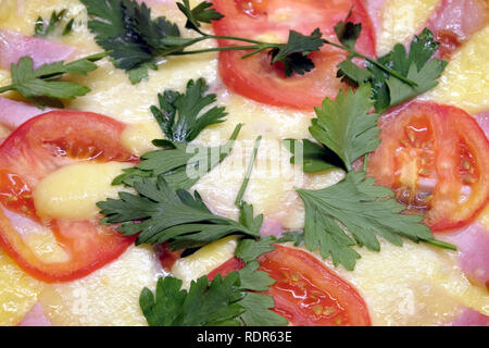 Closeup Fragment der Platte mit vorbereiteten appetitliche Pizza mit Tomaten, Schinken und Käse als Hintergrund der Ansicht von oben Stockfoto