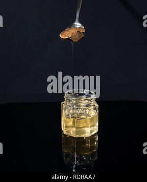 Trüffel Pilz in ein Glas Honig auf schwarzem Hintergrund. Minimalismus in der Komposition. Luxus essen. Freier Platz für Text Stockfoto