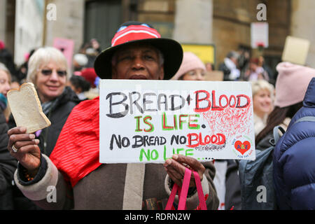London, Großbritannien. Januar 2019. Ein Demonstrant hält ein handgemachtes Schild während des Frauenmarsches in London, Großbritannien, im Januar 2019. Auf dem Schild steht: „BROT + BLUT IST LEBEN. KEIN BROT, KEIN BLUT, KEIN LEBEN“ und ein rotes Herz mit einer Bandage-Illustration. Der Teilnehmer trägt einen roten und schwarzen Hut und Mantel, umgeben von anderen Demonstranten mit Plakaten. Der marsch setzt sich für die Gleichstellung der Geschlechter, soziale Gerechtigkeit und Menschenrechte ein. Penelope Barritt/Alamy Live News Stockfoto