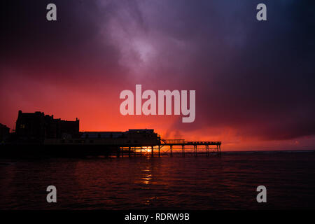 Aberystwyth Wales, Großbritannien, 19. Januar 2019, wie die Sonne sich in Aberystwyth Pier am Ende einer trostlosen feuchten und kalten Januar Tag, Herden von Zehntausenden winziger Stare aus ihrer täglichen Nahrungsaufnahme zurück für die Nacht auf den Wald von Gusseisen Beine unter Victorian seaside Attraktion der Aberystwyth zu Roost. Aberystwyth ist einer der wenigen städtischen Quartieren im Land und zieht Menschen aus der ganzen UK, Zeuge der spektakulären nächtlichen zeigt zwischen Oktober und März. Photo credit Keith Morris/Alamy leben Nachrichten Stockfoto