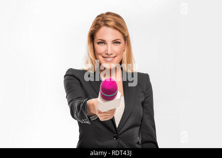 Attraktive Blondine TV-Moderatorin mit einem Mikrofon und zeigt auf ein Objekt. Stockfoto