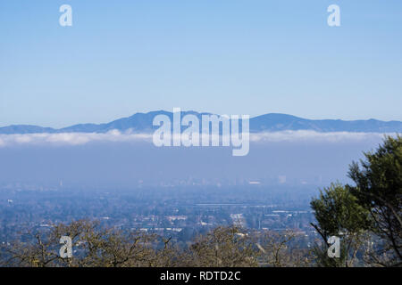 Blick in Richtung Mt Hamilton Gipfel (und der beobachtungsstellen) in Diablo mountain range; Cupertino und San Jose Downtown sichtbar unter einer Schicht von Wolken; Sil Stockfoto