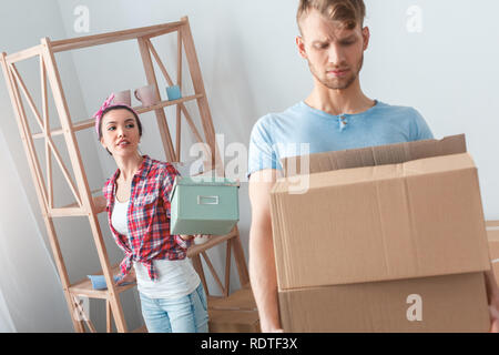Junges Paar, der seinen neuen Platz stehende Frau, die Schatulle Mann box besorgt Stockfoto