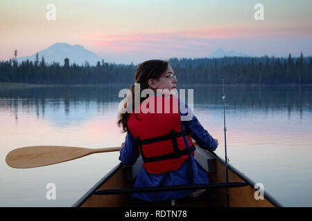 Mädchen paddeln Kanu auf Hosmer See in der Abenddämmerung, Berg Bachelor im Hintergrund, Cascade Lakes, Oregon, USA Stockfoto