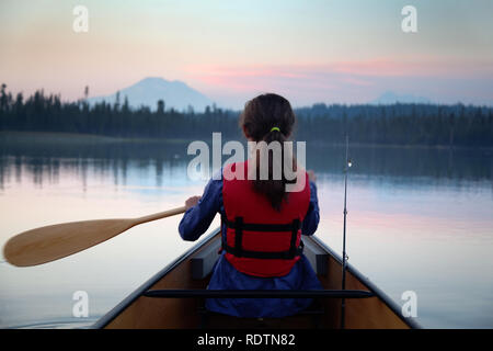 Mädchen paddeln Kanu auf Hosmer See in der Abenddämmerung, Berg Bachelor im Hintergrund, Cascade Lakes, Oregon, USA Stockfoto