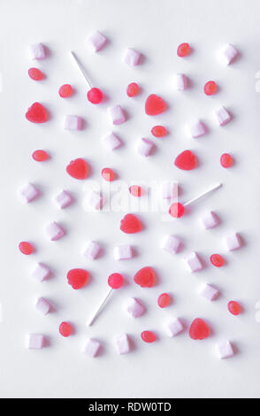 Rosa Bonbons und Marshmallows Muster auf weißem Hintergrund. Verschiedene rosa Bonbons für Valentinstag im Hintergrund, Ansicht von oben. Stockfoto