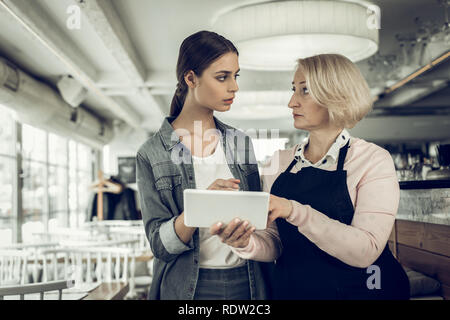 Dunkelhaarige Kellnerin tragen Jeanshemd im Gespräch mit Arbeitgeber Stockfoto