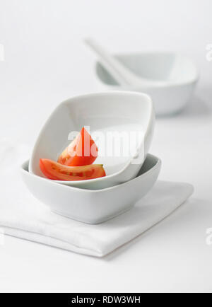 Scheibe Tomate in eine leere weiße Schüssel gelegt. Stockfoto
